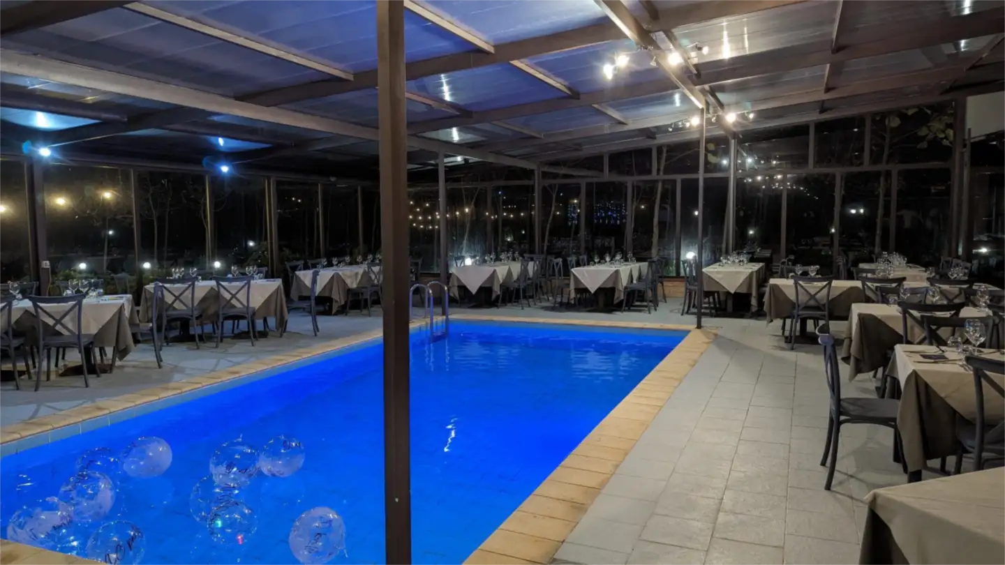 La piscina coperta e la sala da pranzo illuminate di sera